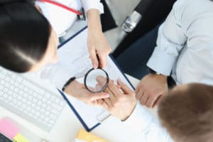 Dermatologist looking at patients skin on hands with magnifying glass top view. Eczema treatment concept