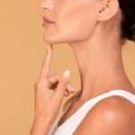 young woman touching her face, happy with result of plastic surgery