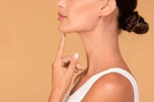 young woman touching her face, happy with result of plastic surgery