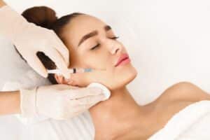 Woman relaxing with eyes closed while receiving Juvederm injections in her face.