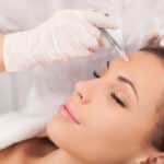Woman receives a Botox injection between her brows to minimize frown lines.
