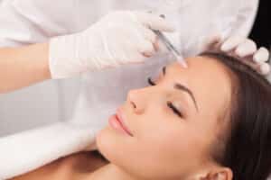 Woman receives a Botox injection between her brows to minimize frown lines.