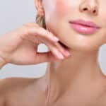 Woman with a lot of makeup reveals a tight chin and neck following her Kybella treatment to reduce submental fat.