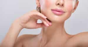 Woman with a lot of makeup reveals a tight chin and neck following her Kybella treatment to reduce submental fat.