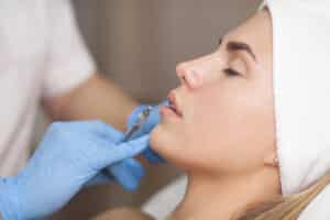 Woman relaxes as an expert injector prepares to add volume to her lips
